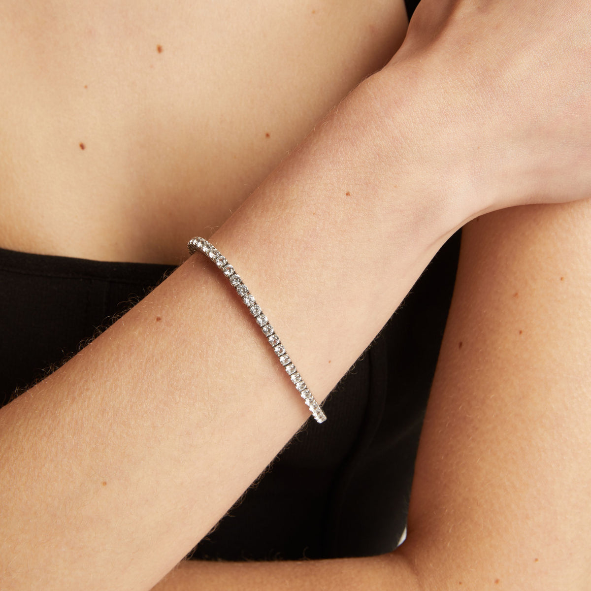 Model. Tennis bracelet on a wrist with a black top.