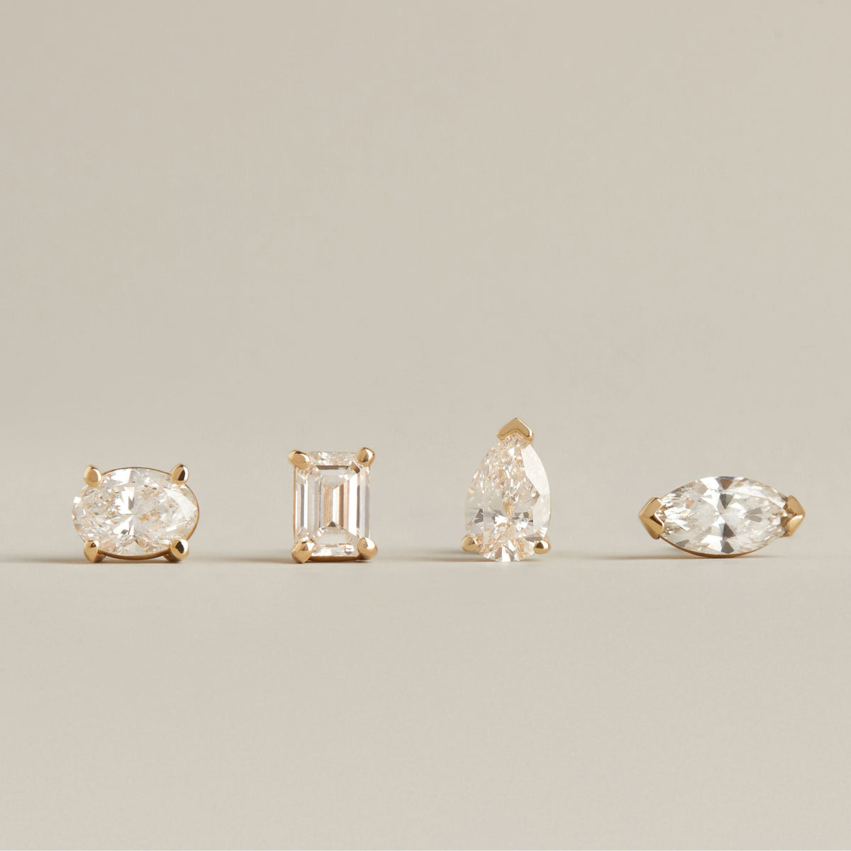 Model. Four different shape diamond stud earrings on neutral background