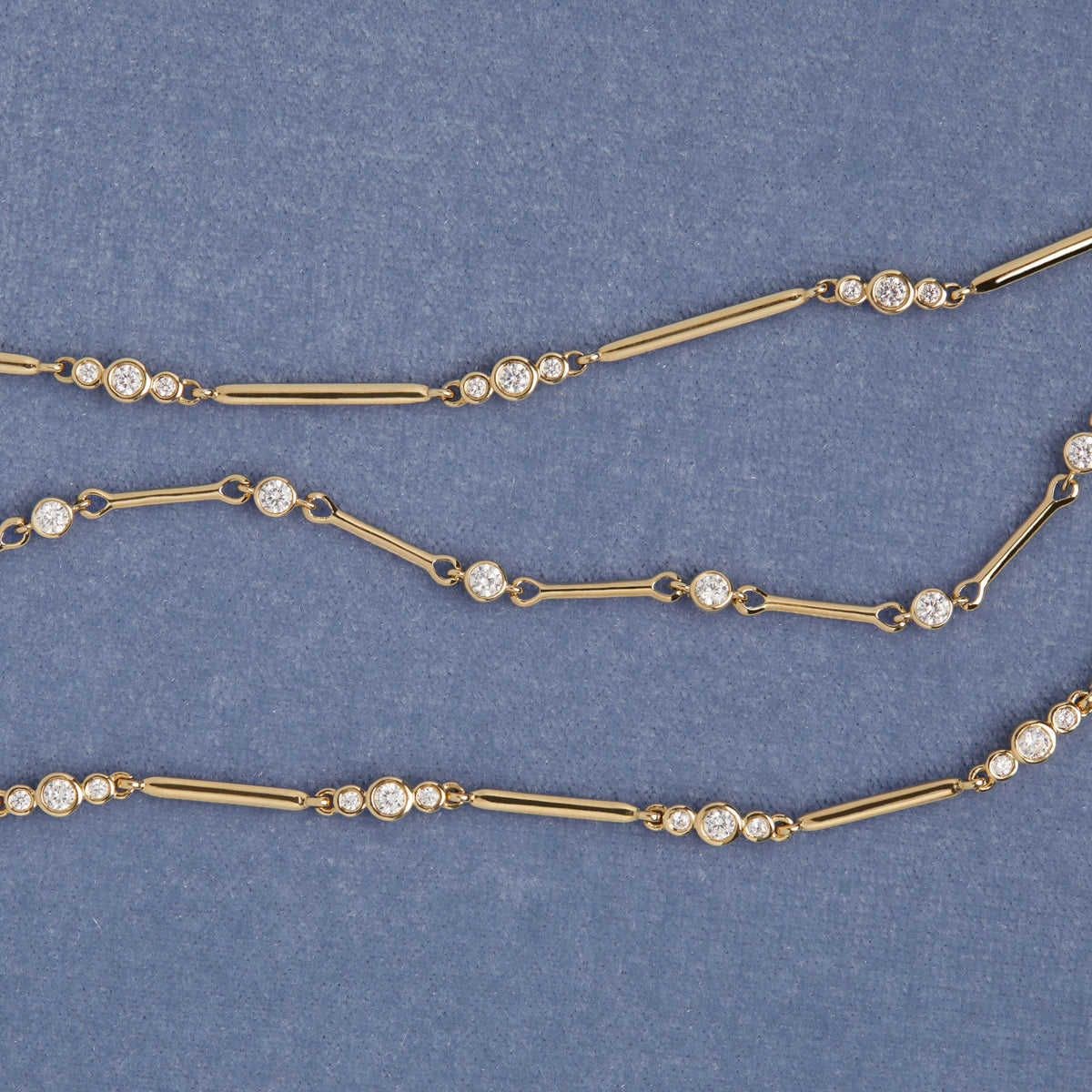 Model. Three gold bracelets with bezel diamonds on blue background