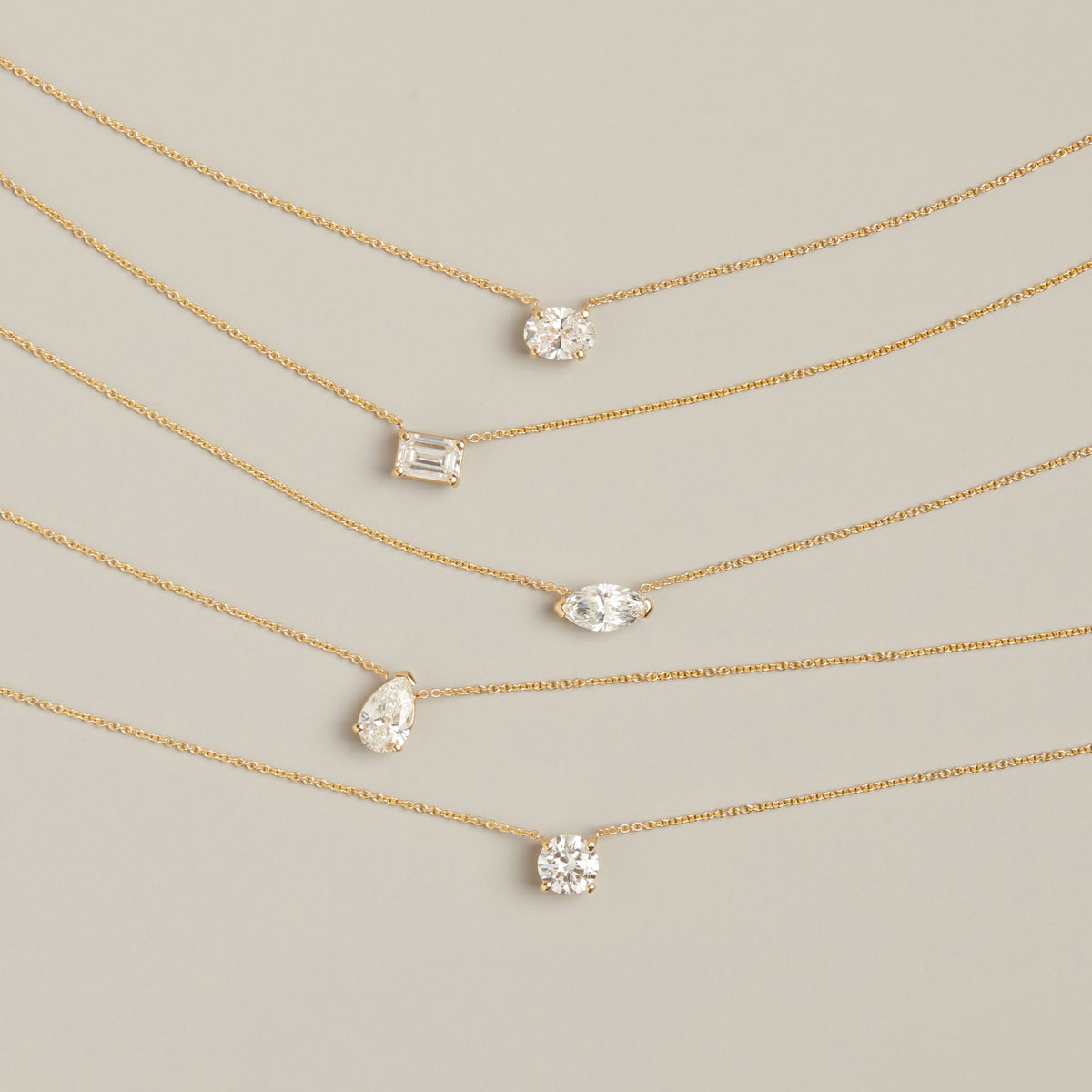 Model. Five gold chain necklaces with different shaped diamonds on neutral background