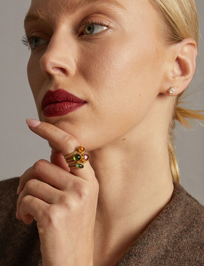 Model. Close-up of a woman wearing rings with gemstones on a neutral background
