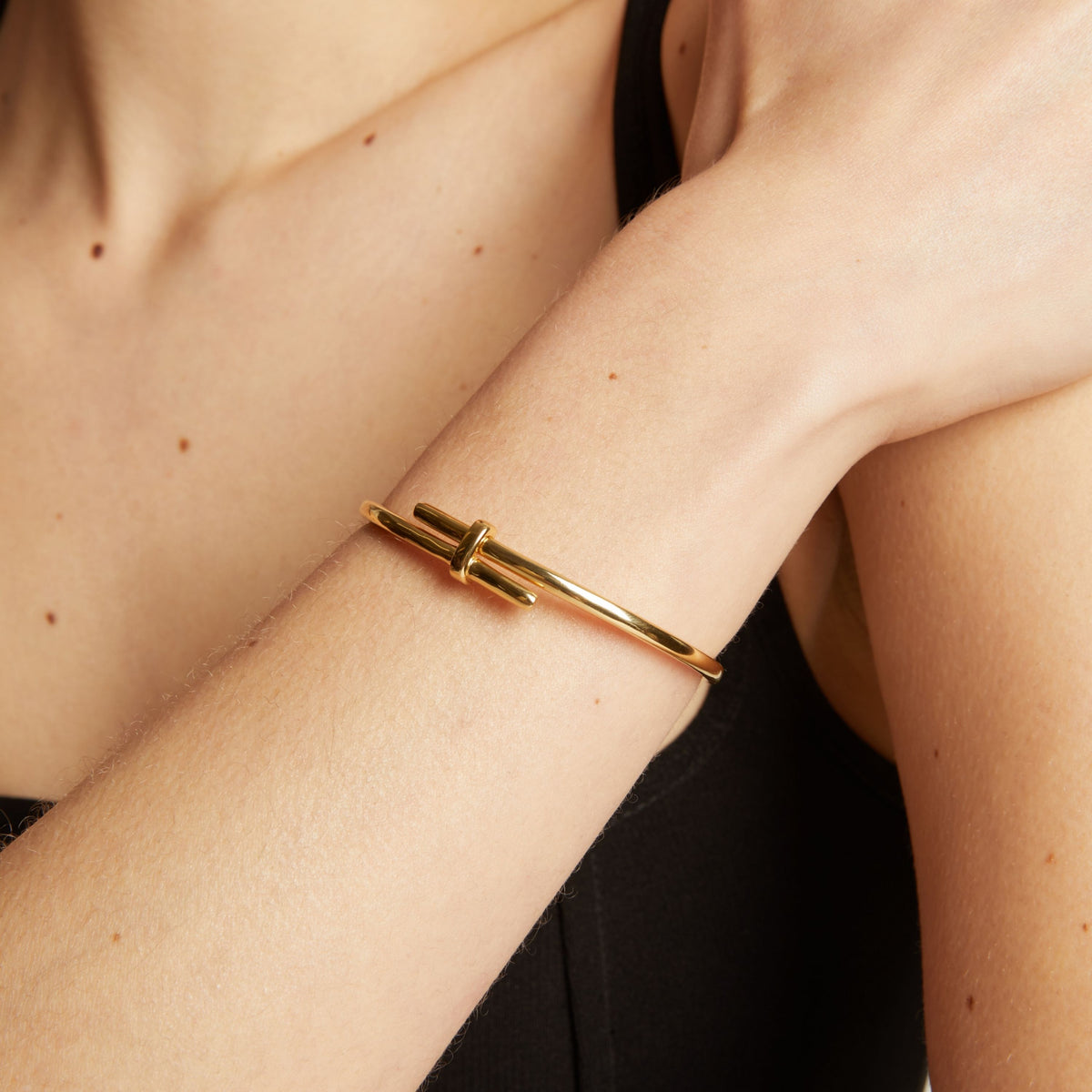 Gold bracelet on a person's wrist with a neutral background.
