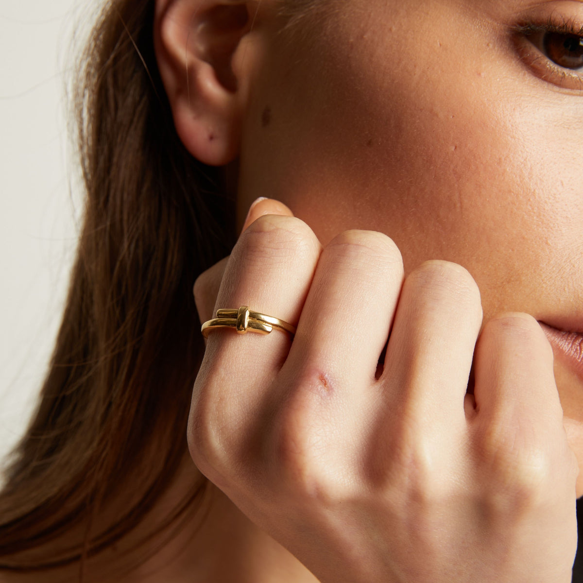 Model. Close up of a person wearing a gold ring on their finger.