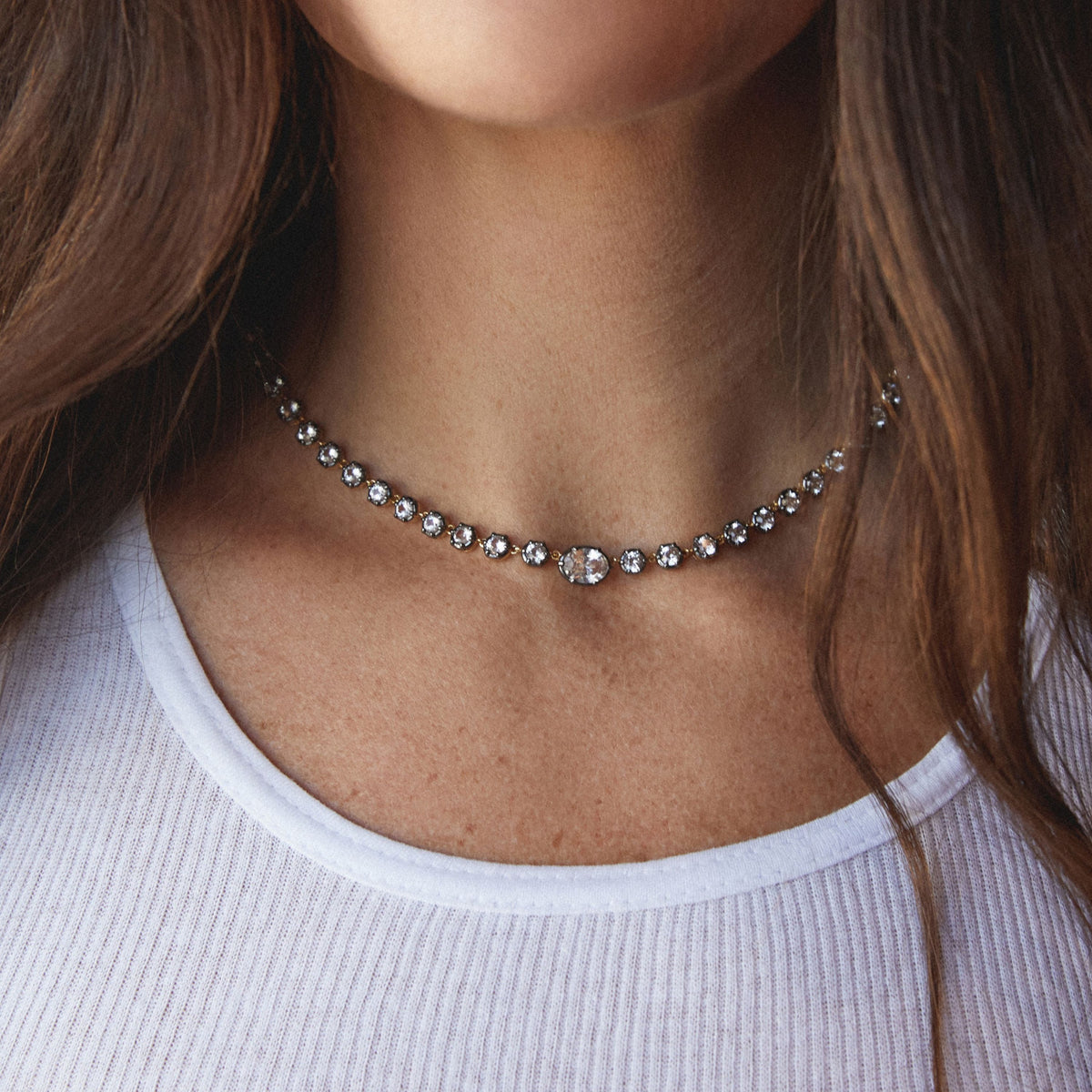 Model. Close up of a woman in a white top wearing a Georgian set tennis necklace.