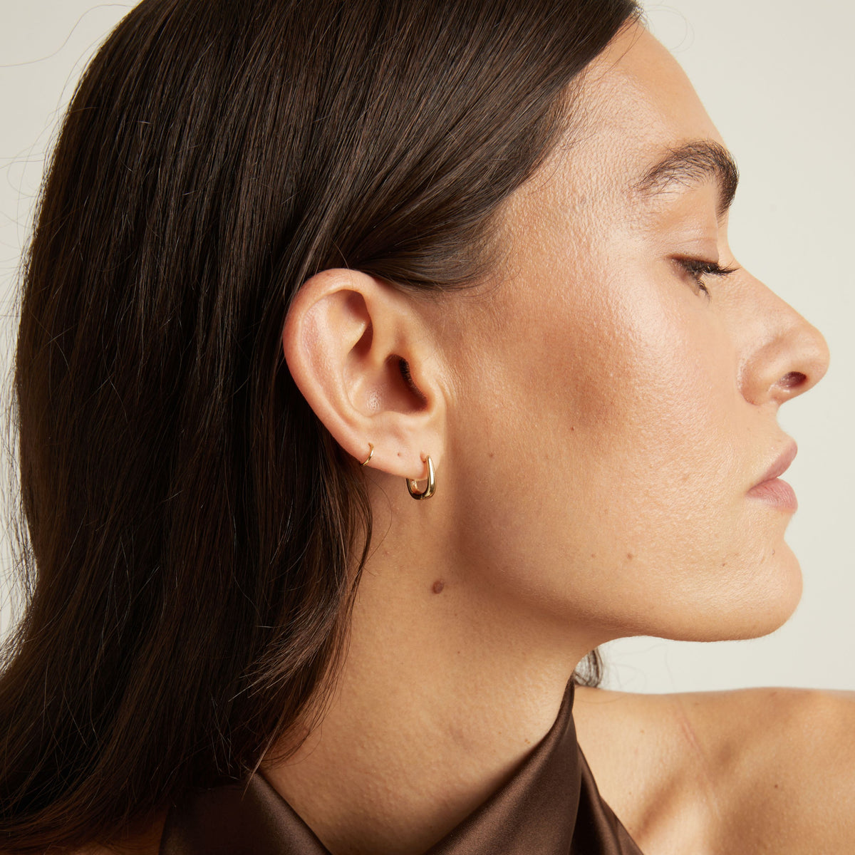 Close up of woman wearing gold huggie earring.