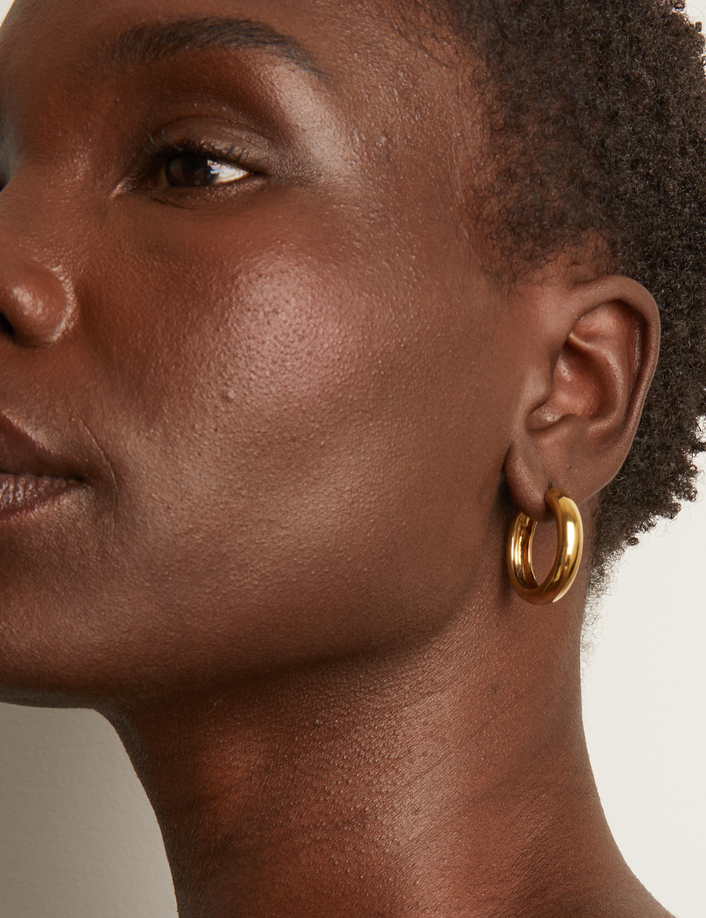 Model. Close up of woman with short brown hair wearing gold hoop earring
