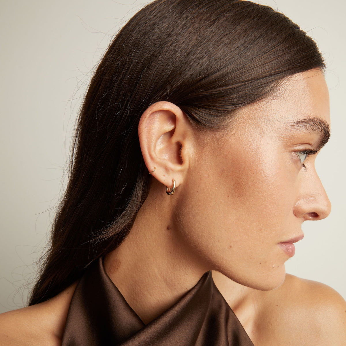 Close up of woman wearing gold huggie earring.
