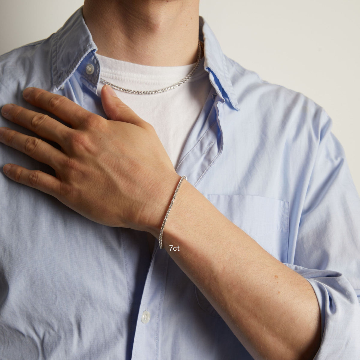 Model. A close-up of a man's wrist wearing a delicate tennis bracelet, shown against a light blue button-down shirt.