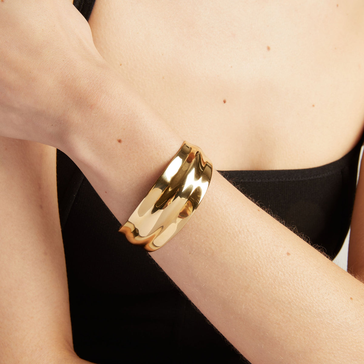 Close up of a gold cuff bracelet.