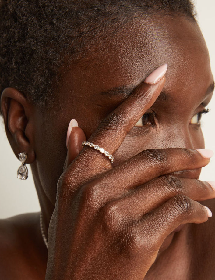 Model. Woman wearing earrings and a ring with a neutral background