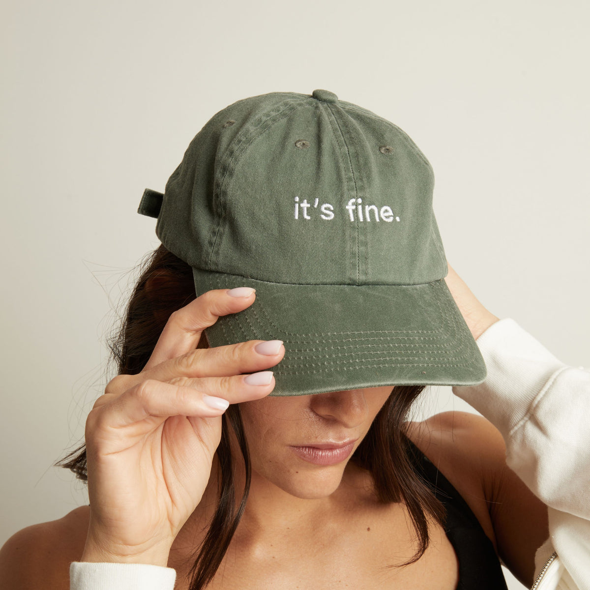 Woman wearing a green cap with 'it's fine' text on a plain background