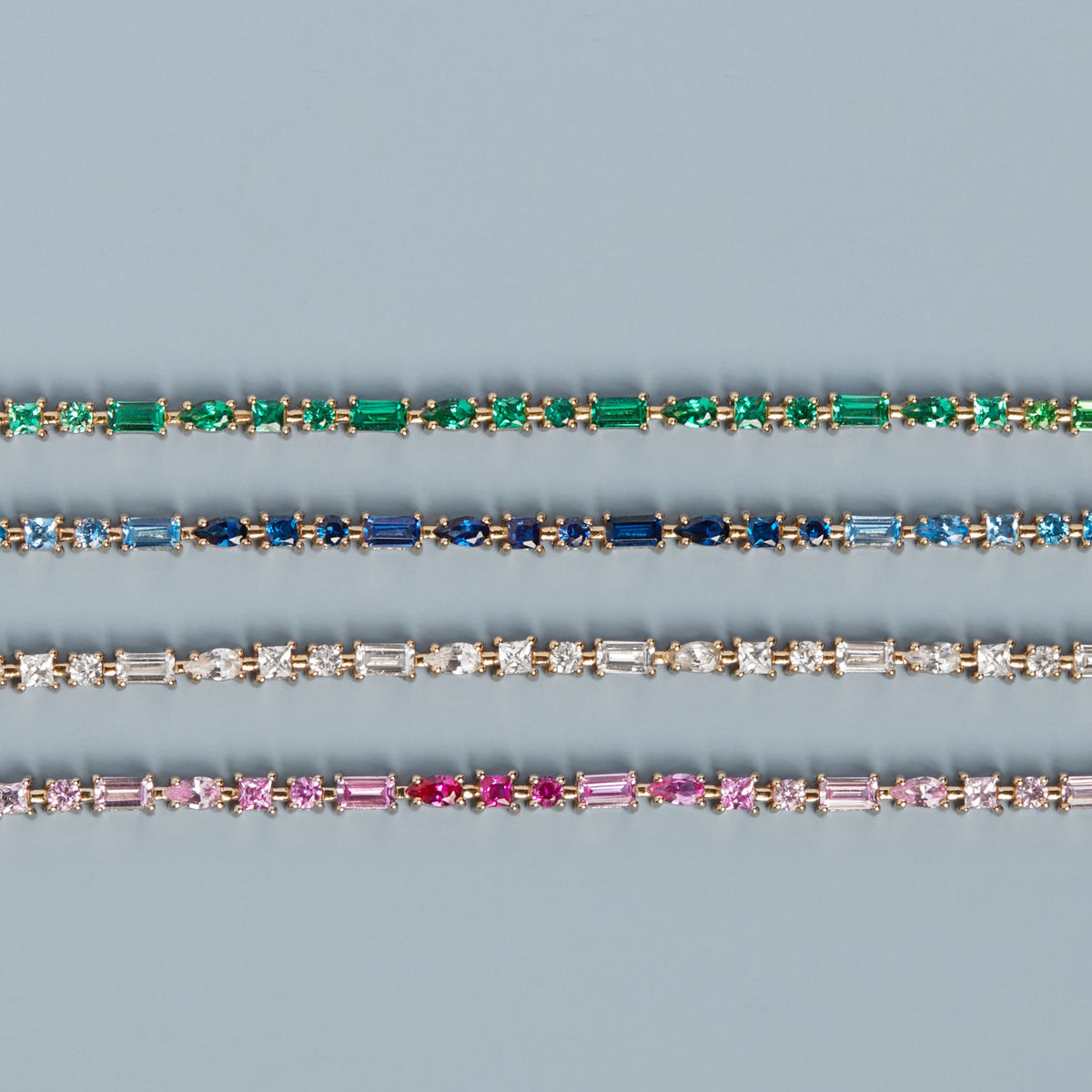Model. Three diamond bracelets with different colored gemstones on a blue background