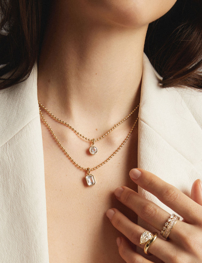 Model. Woman wearing stacked gold necklaces with gemstone pendants