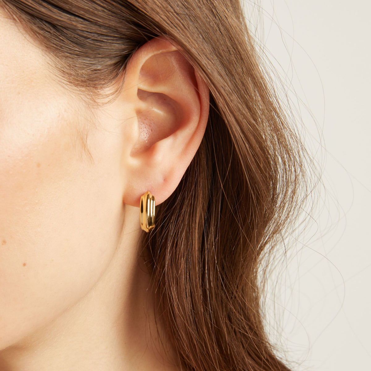 Close up of a person wearing gold hoop earrings.