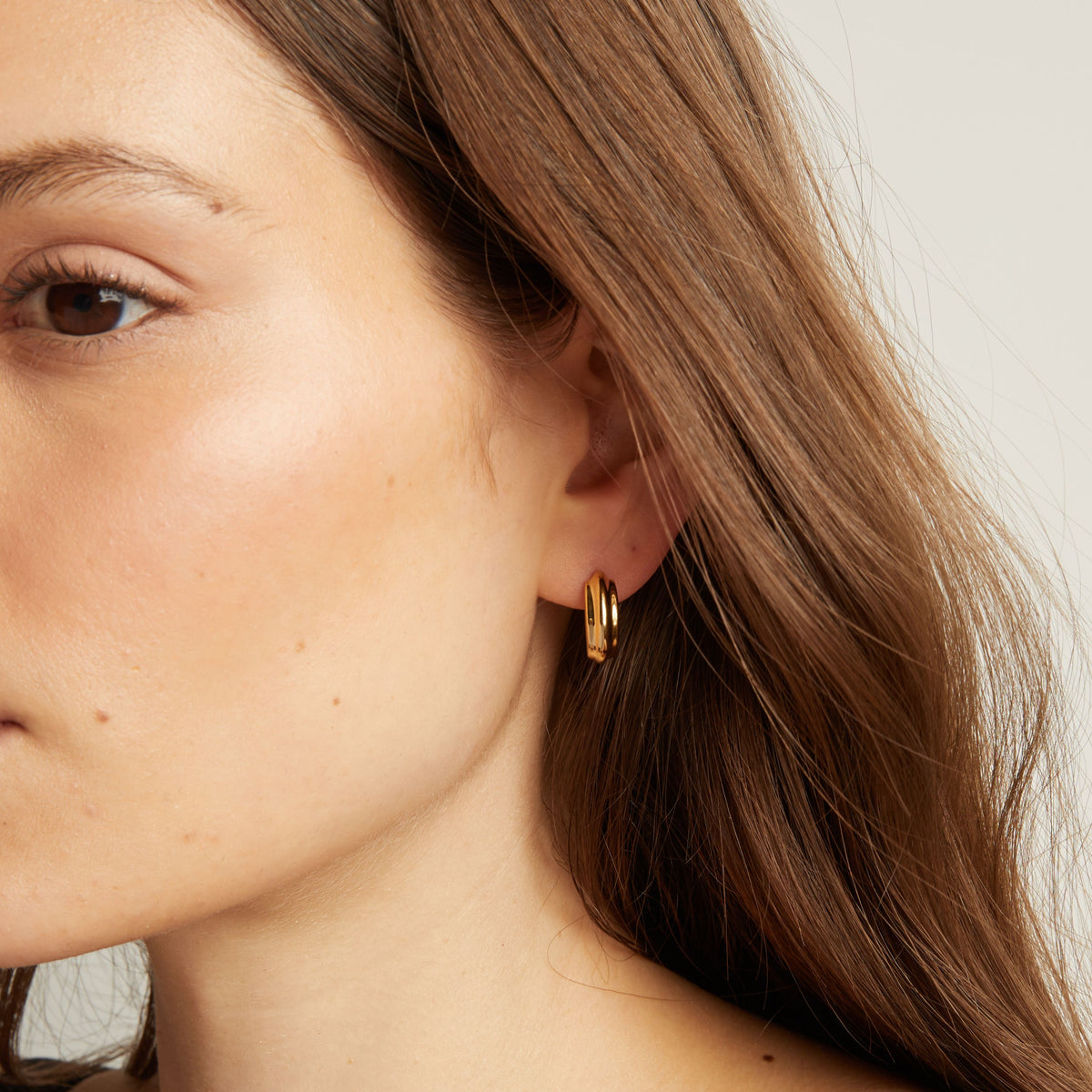 Close up of a person wearing gold hoop earrings.
