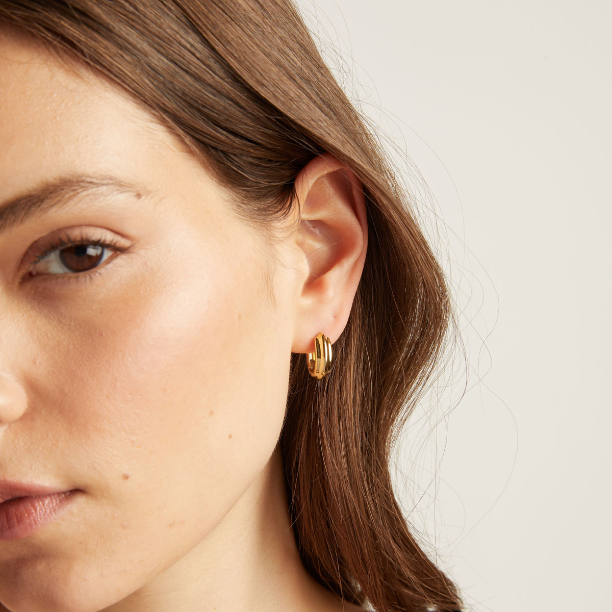 Close up of a person wearing gold hoop earrings.