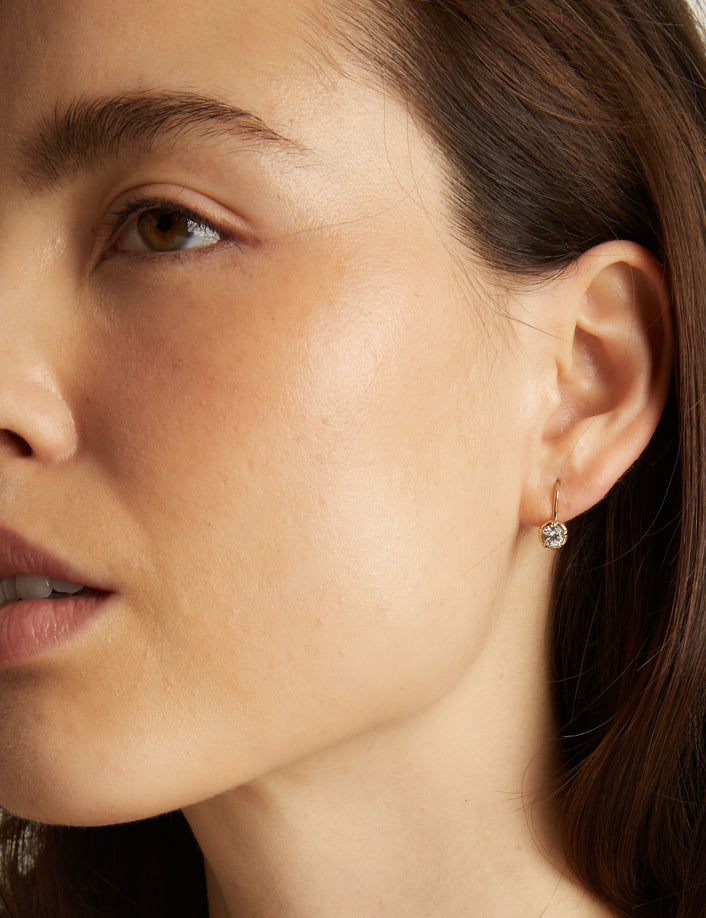 Model. Close-up of a woman wearing a diamond earring with a neutral background