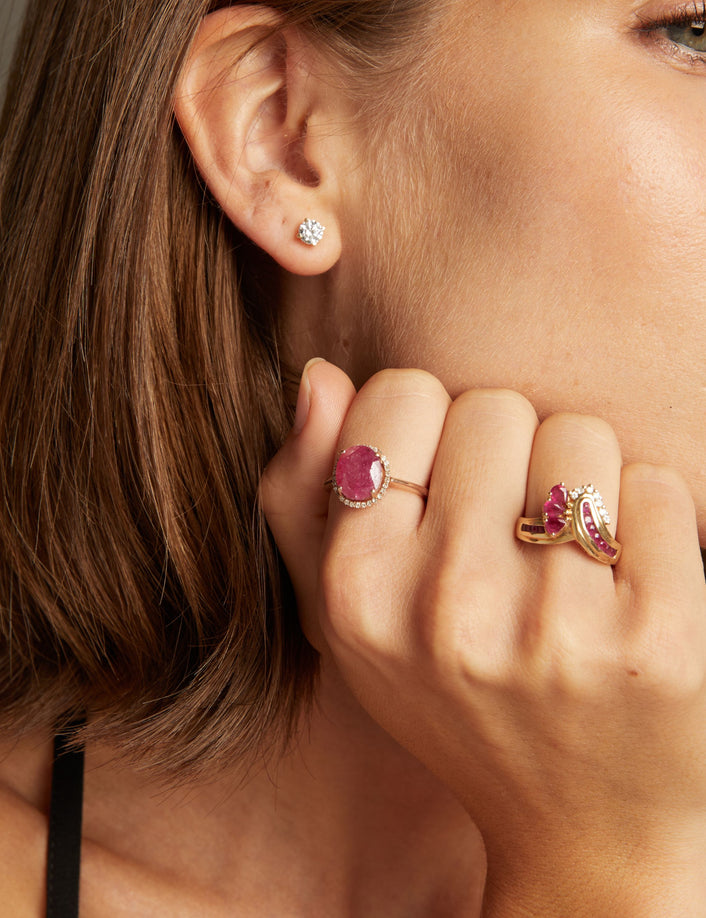 Model. Close up of woman wearing red ruby statement rings on neutral background. 