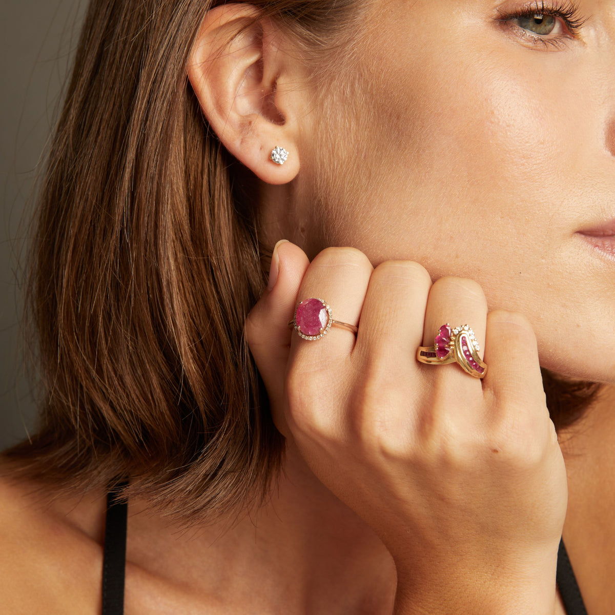 Model. Close up of woman wearing red ruby statement rings on neutral background. 