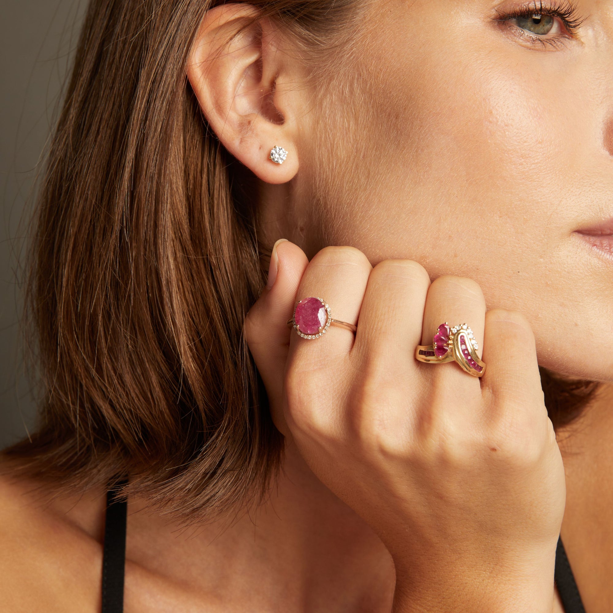 Model. Close up of woman wearing red ruby statement rings on neutral background. 