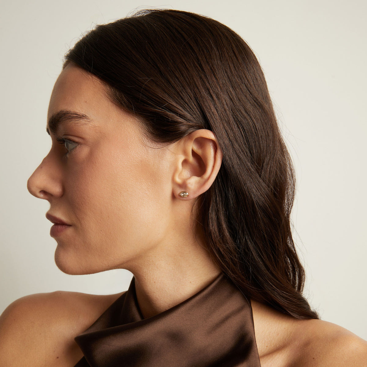 Model. Close up of a woman wearing a bezel stud earring.