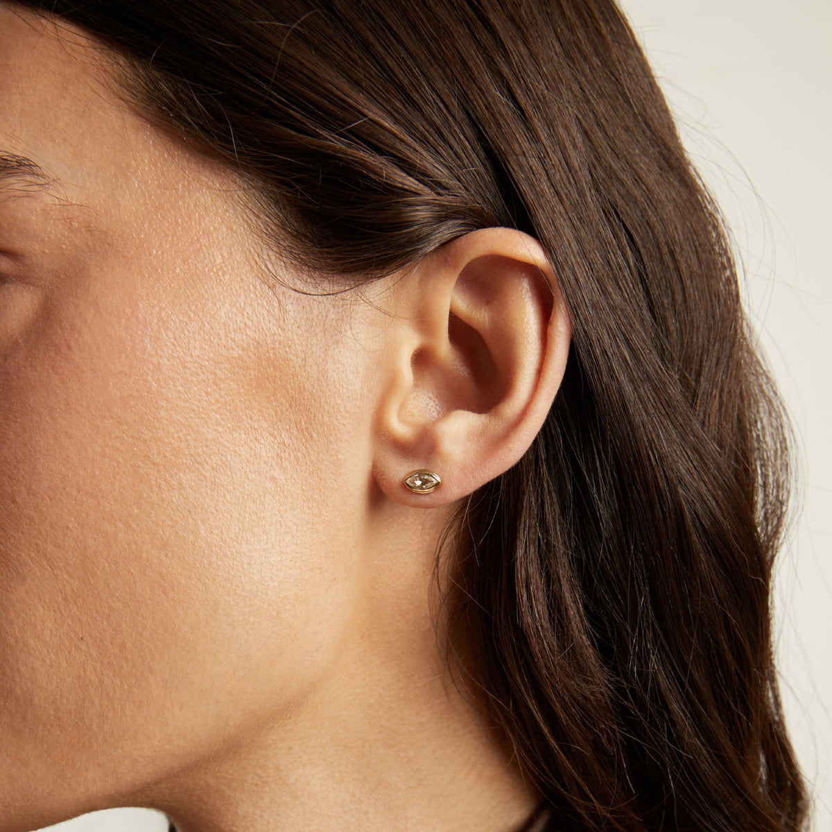 Model. Close up of bezel stud earring on woman's ear.