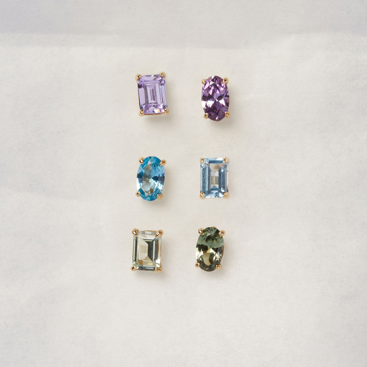 Model. Three sets of gemstone earrings on a light gray background