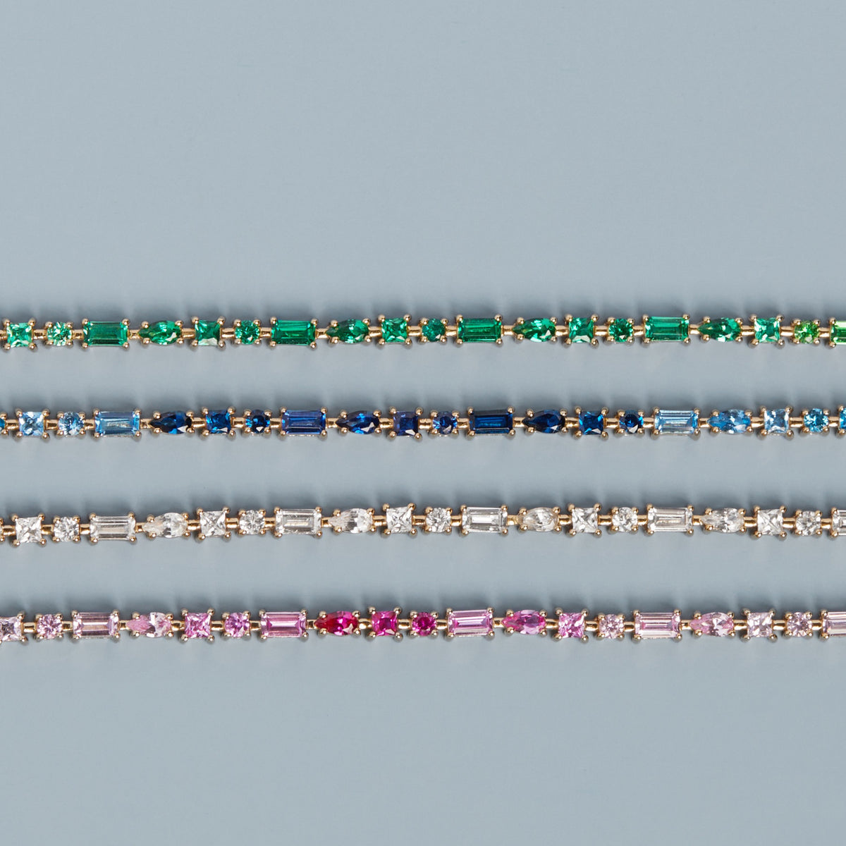 Model. Three diamond bracelets with different colored gemstones on a blue background