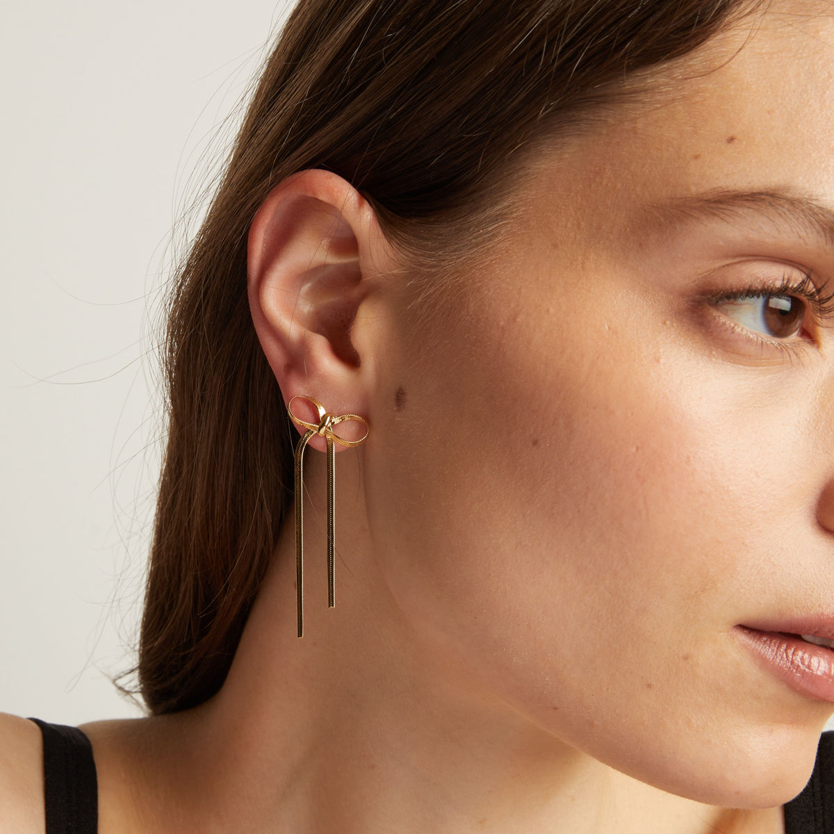 Model. Close up of woman wearing bow earrings. 
