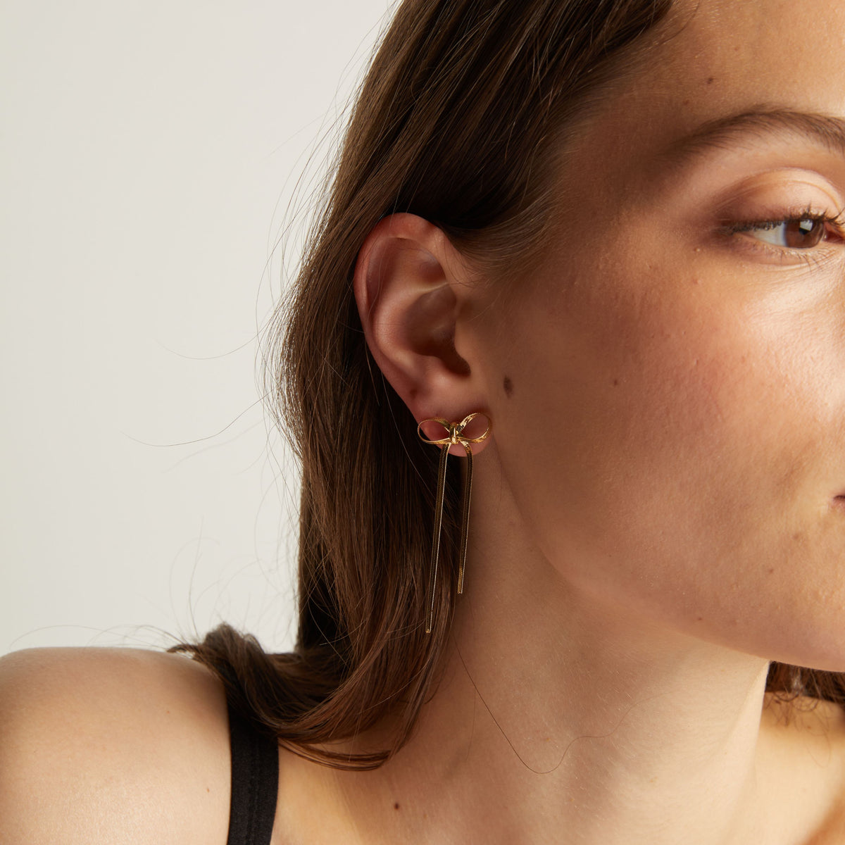 Close up of woman wearing bow earrings. 