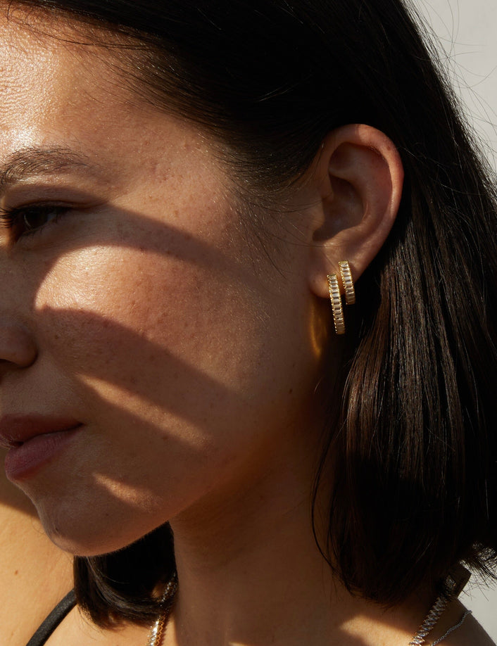 Model. side profile of woman wearing two hoop earrings 