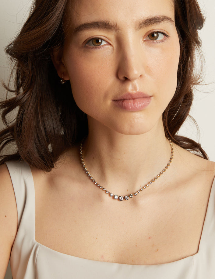 Model. Woman in light top wearing a diamond necklace. 