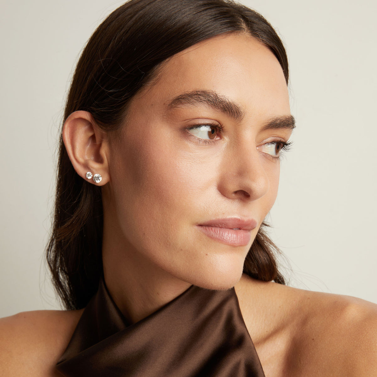 Model. Close up of a woman wearing two diamond stud earrings. 