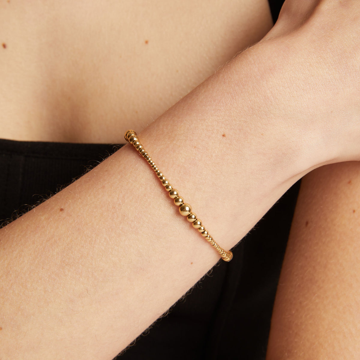 Gold bracelet on a person's wrist with a neutral background.