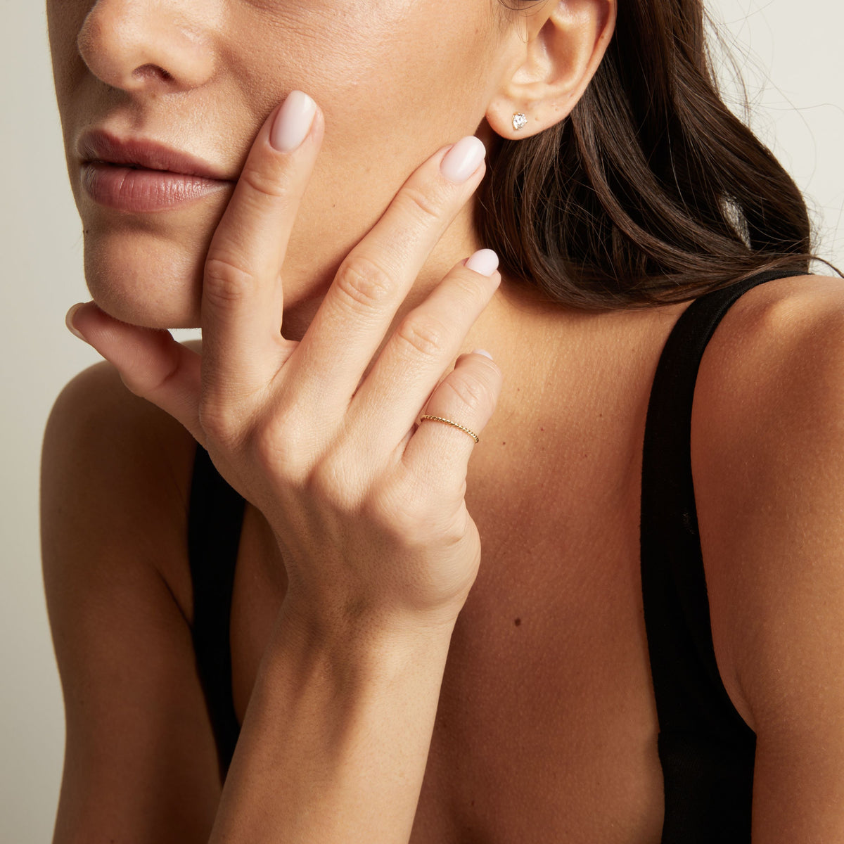 A close-up lifestyle shot of a woman wearing a delicate, thin gold twisted ring.