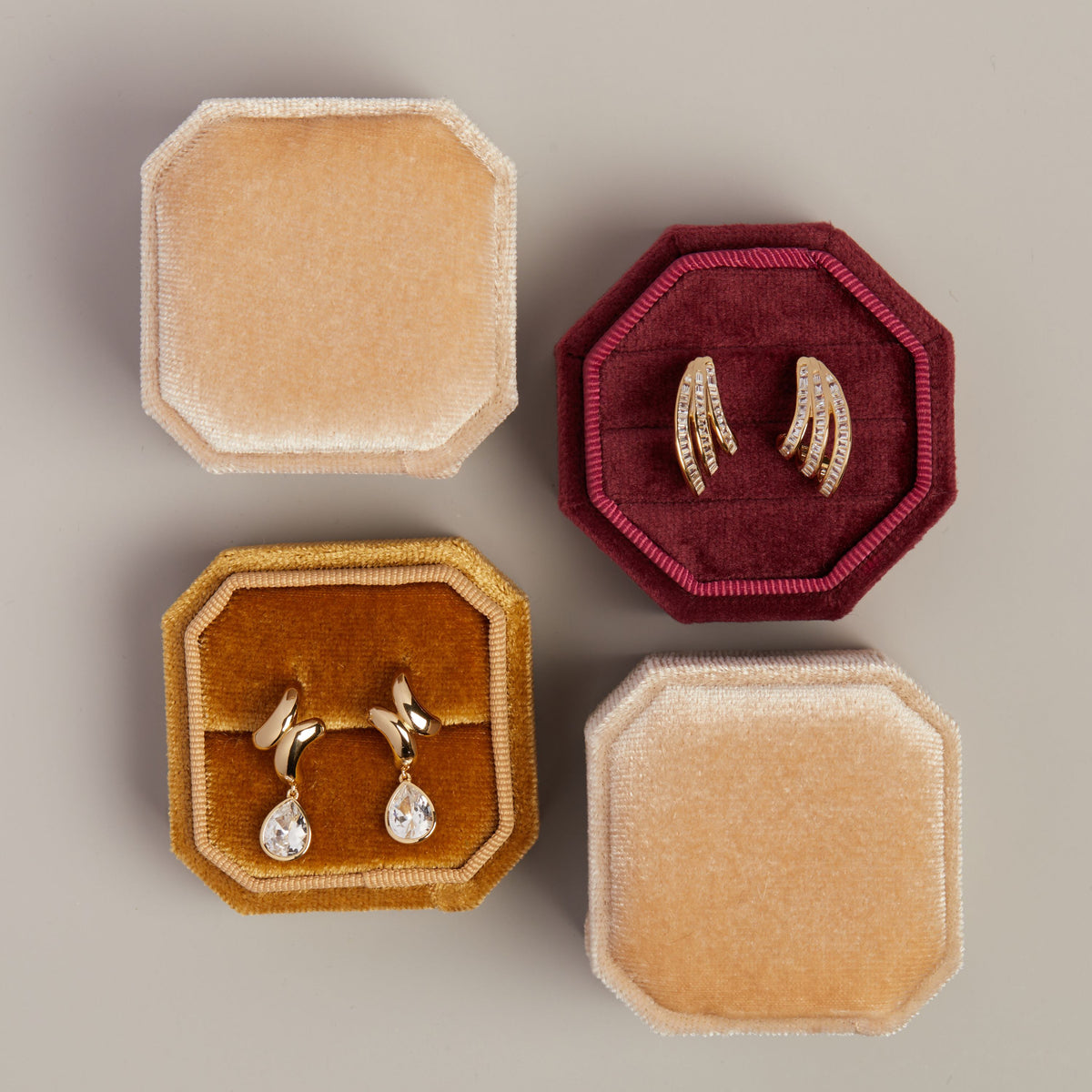 Model. Close flat lay image of two earrings in yellow and red velvet earring boxes on neutral background.