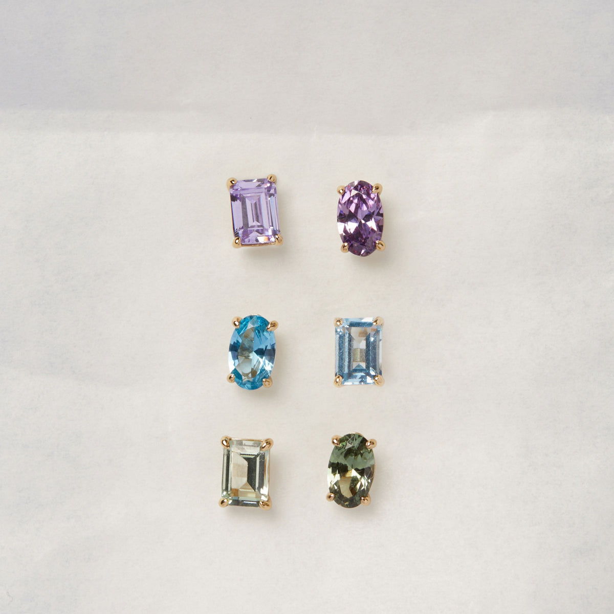 Model. Three sets of gemstone earrings on a light gray background