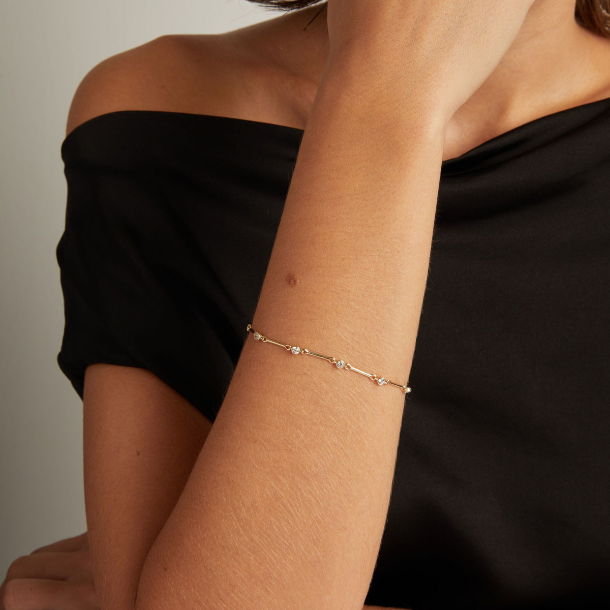 Model. Close up of woman's wrist with a diamond bar bracelet on black shirt. 