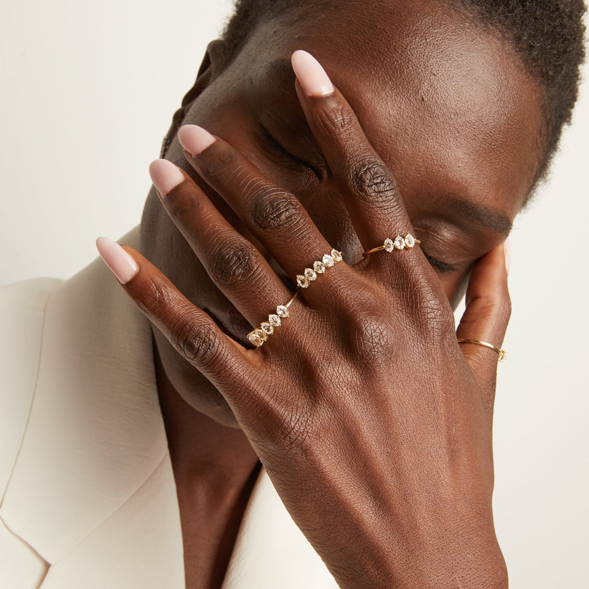 Model. Woman wearing various rings with white sapphire gemstones.