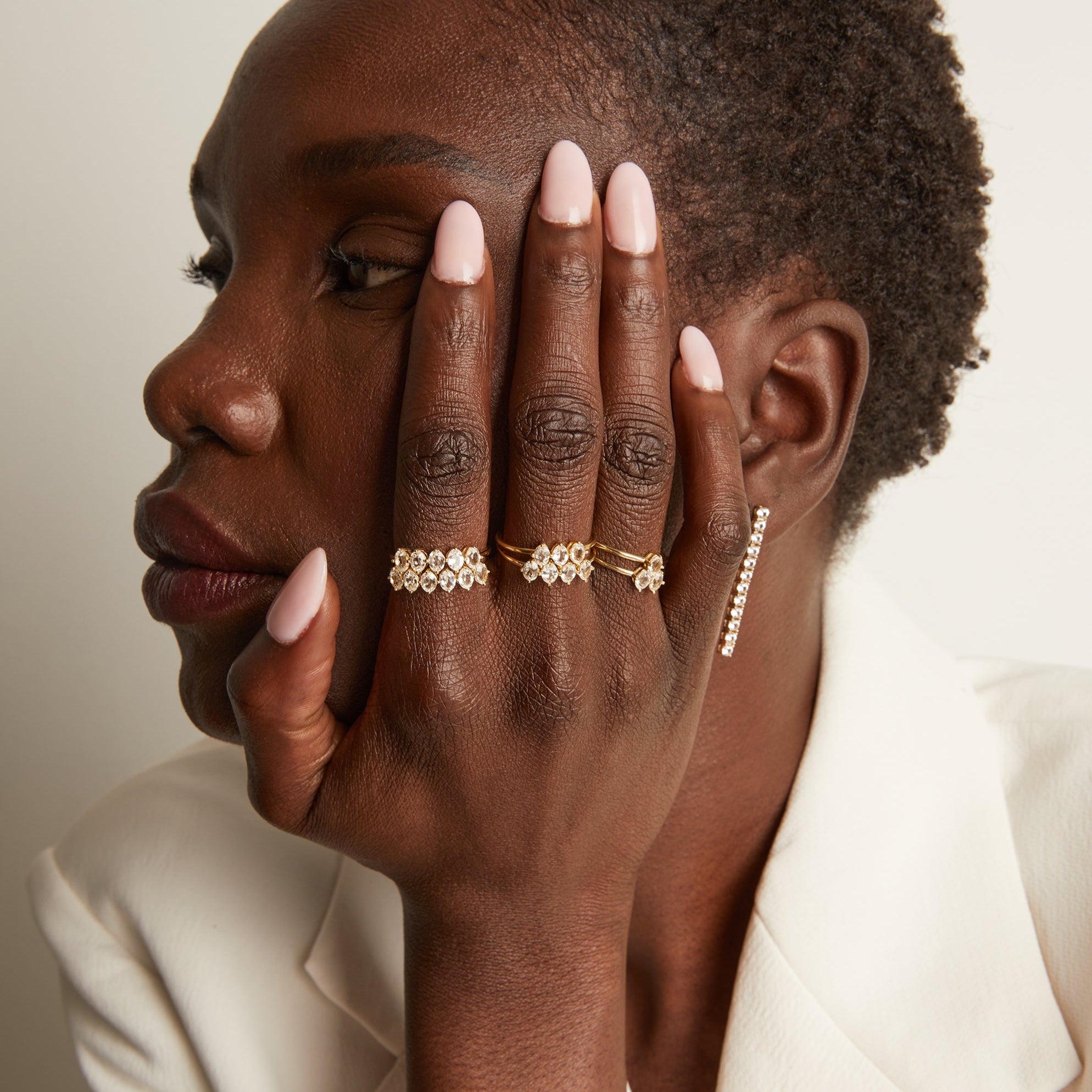 Woman wearing various rings with white sapphire gemstones.