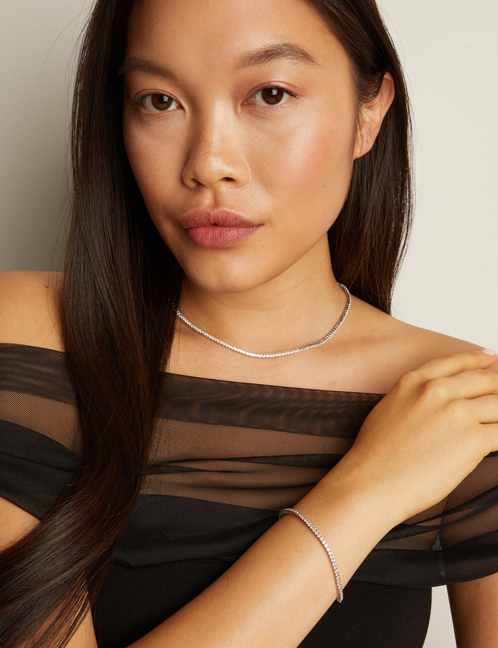 Model. Woman wearing a black sheer top with a plain background