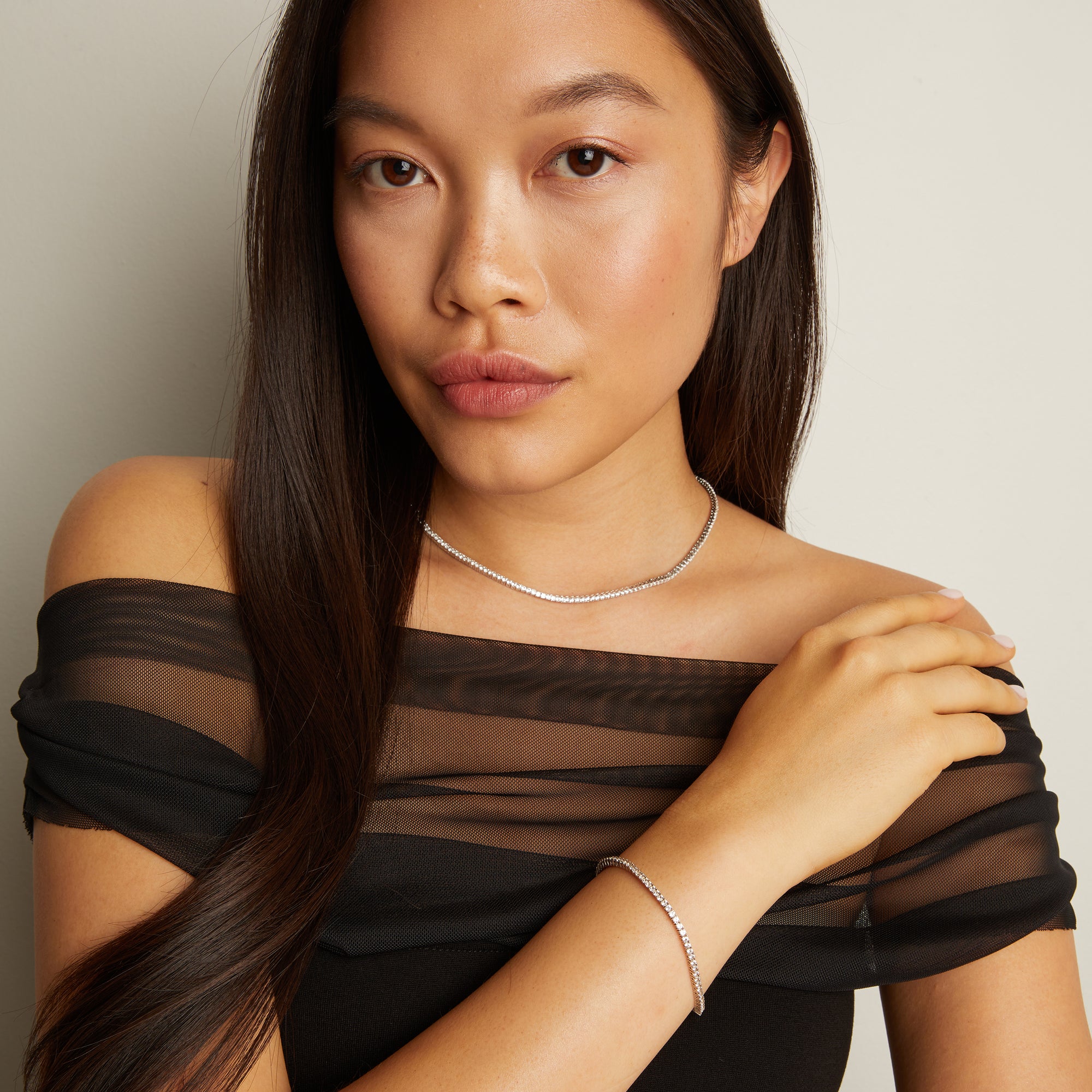 Model. Woman wearing a black sheer top with a plain background