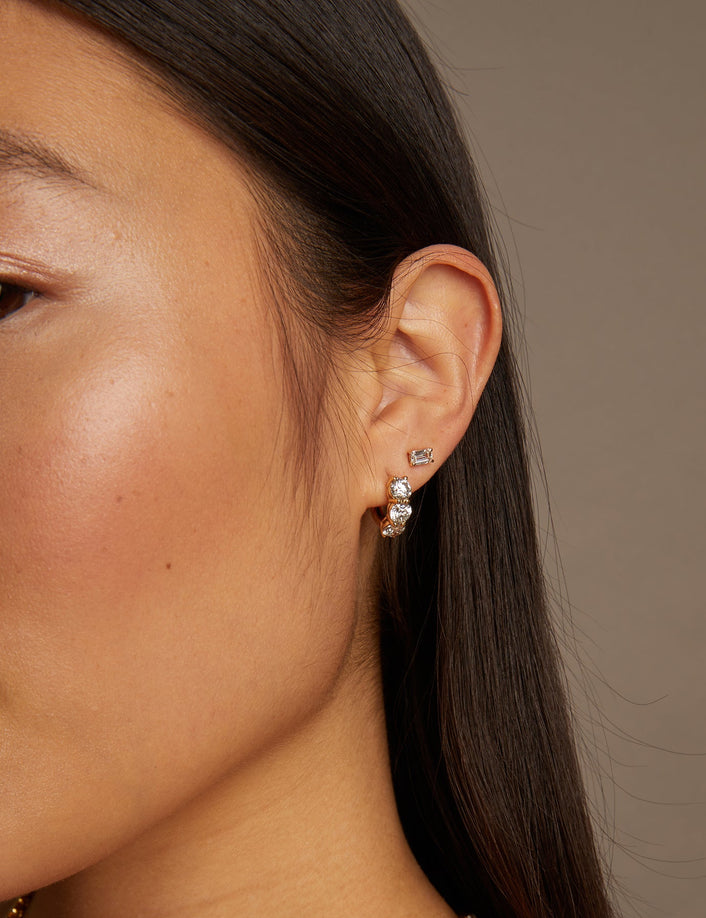 Model. Close-up of a woman wearing gold necklace and earrings against a neutral background