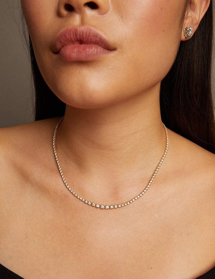 Model. Close-up of a woman wearing a delicate necklace and earrings against a neutral background