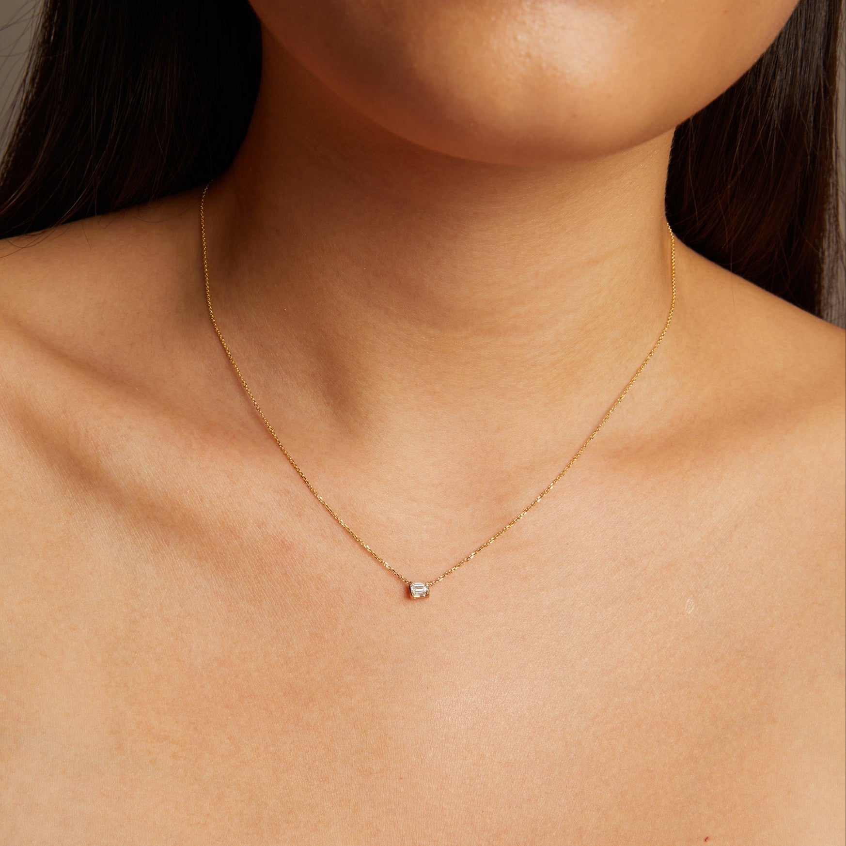 Model. Gold necklace with a small diamond pendant on a person's neck