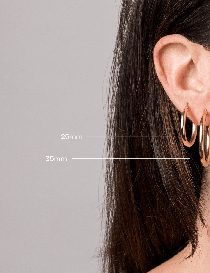 Model. Yellow gold hoop earrings worn by a person with measurements indicated on a gray background