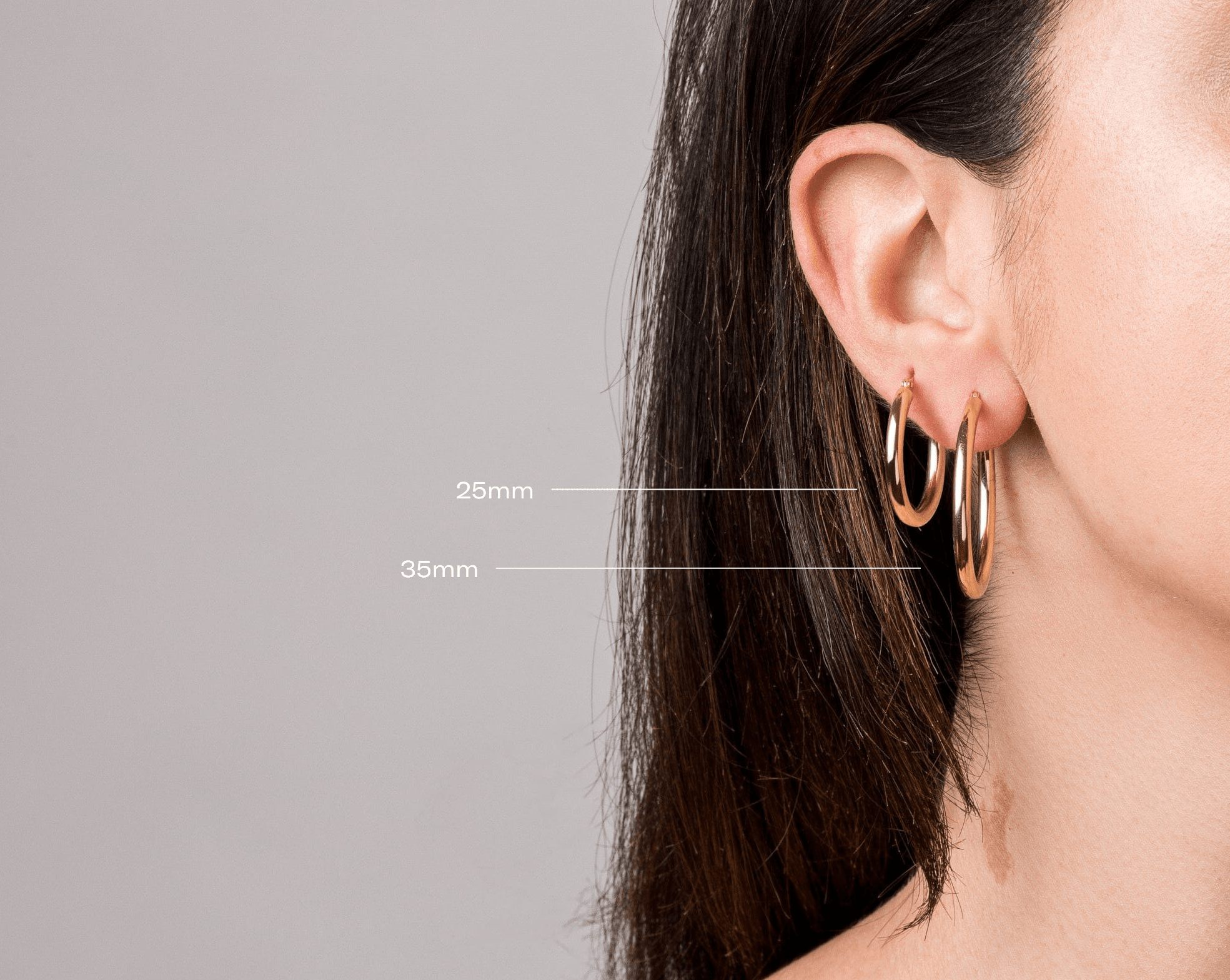 Model. Yellow gold hoop earrings worn by a person with measurements indicated on a gray background