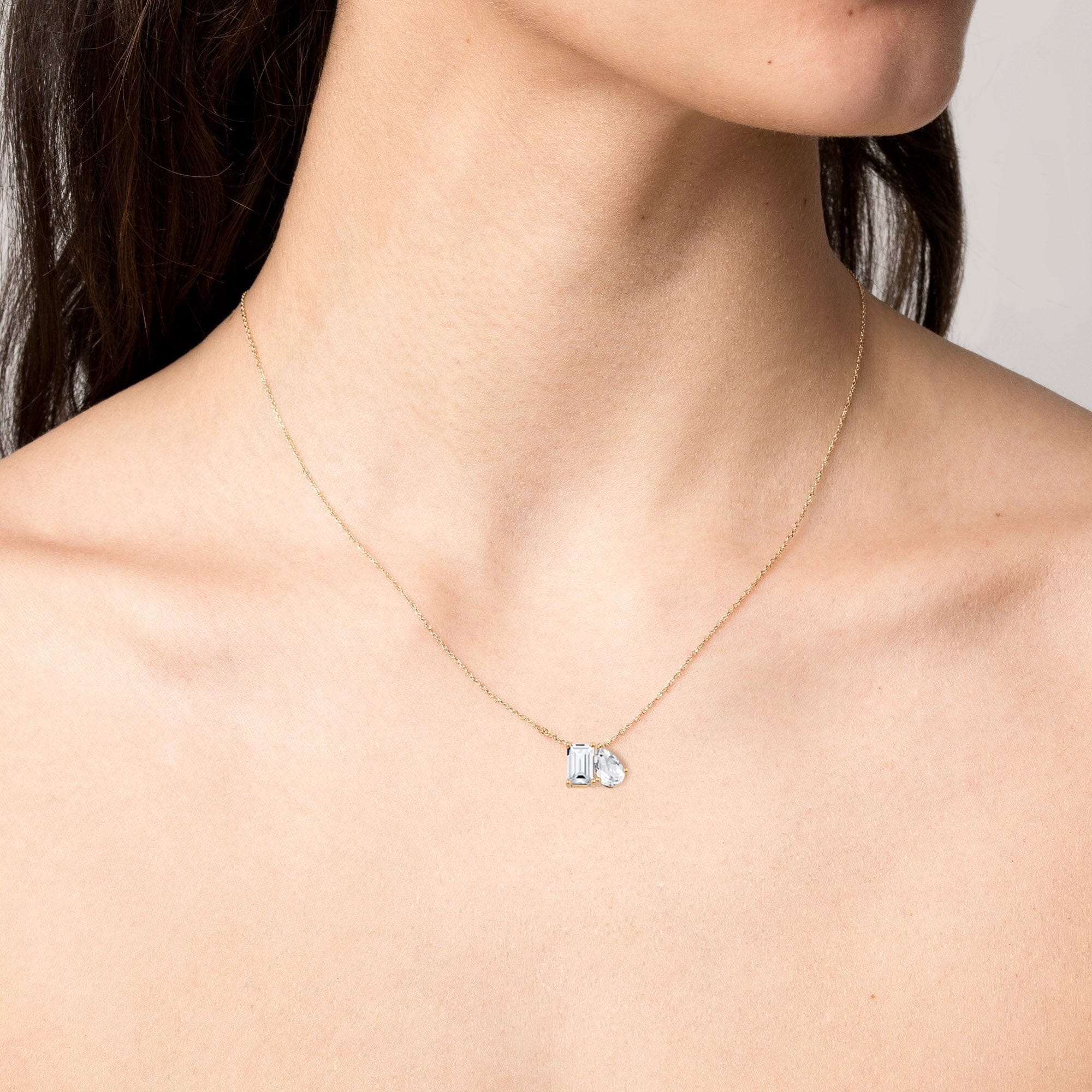 Model. Gold necklace with a pendant on a person's neck against a neutral background