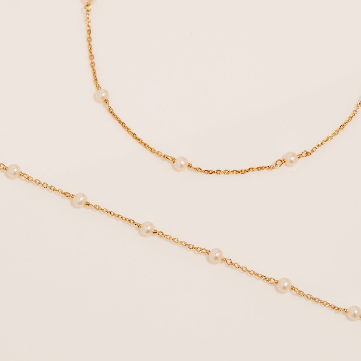 Flatlay Model. Two chains with pearls laying on white surface 