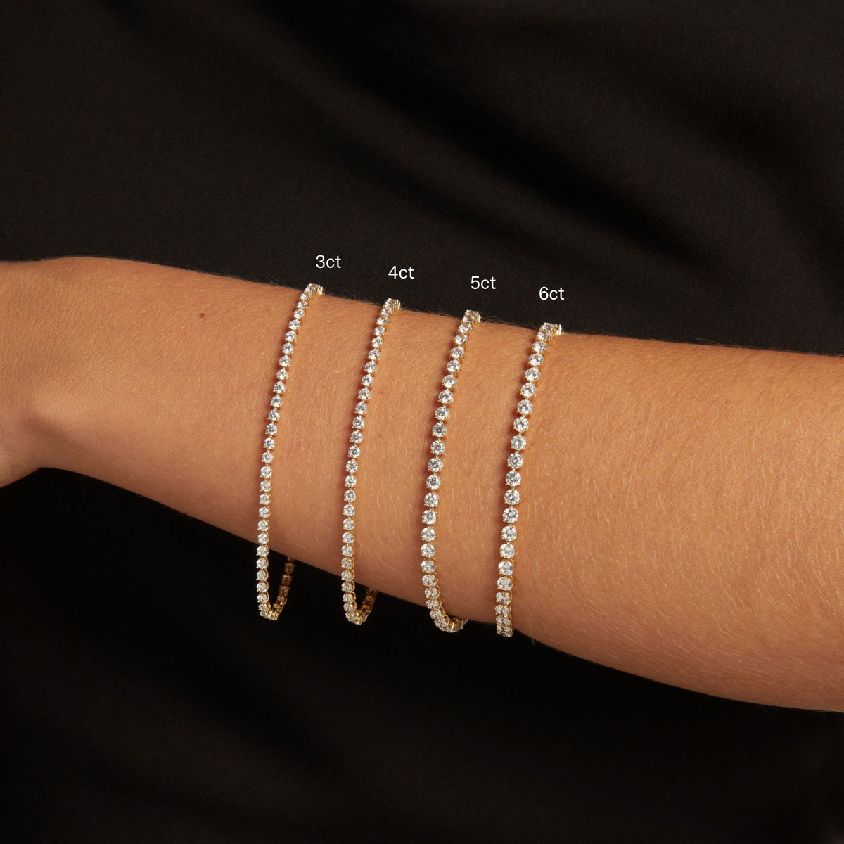 Model. Close up of a woman's wrist with four dainty diamond tennis bracelets. 